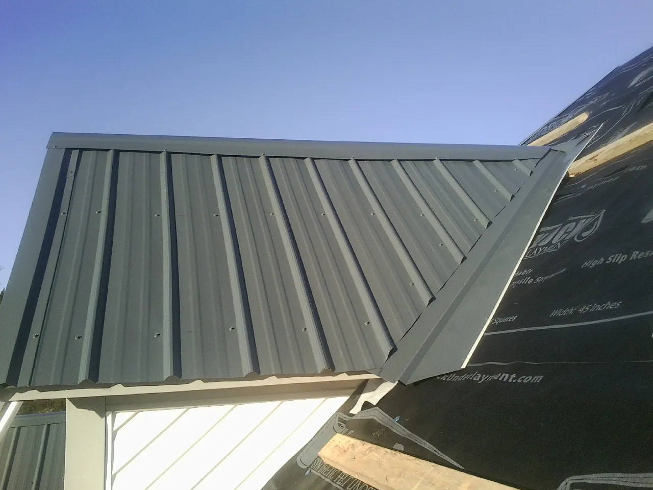 Gray metal roof panels going on over a garage gable in Slovan