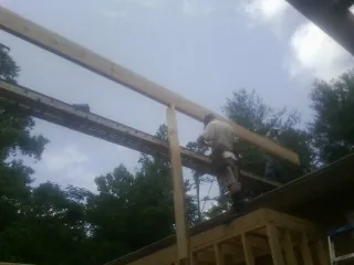 Carpenter setting a ridge beam over a new addition frame — Ice Dam Removal by Roofing Brothers in Slovan