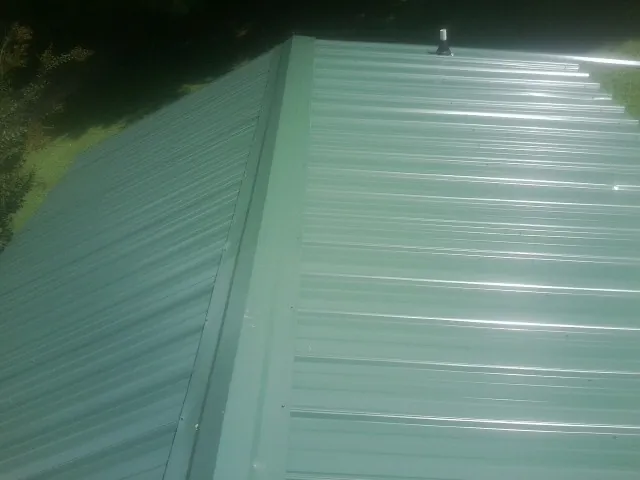 New green metal panels meeting at the ridge of a roof — Flat Roof Repair work by our crew in Slovan