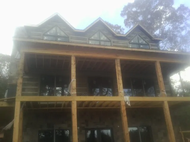 Dormers and porch framing on a large log home under construction — Roof Coating work by our crew in Slovan