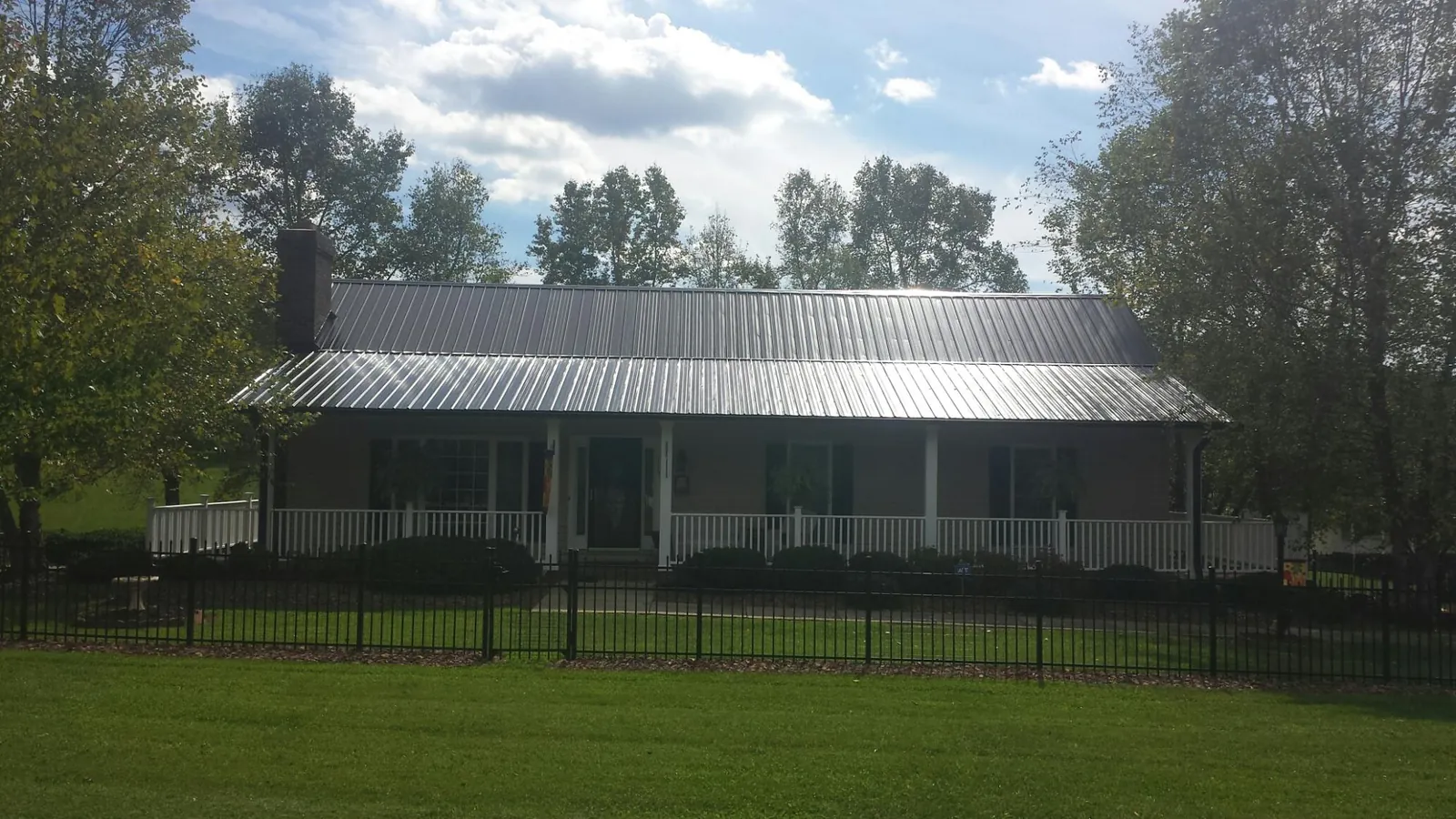 Gray metal roof on a brick ranch with a full width front porch — Gutter Guard Installation work by our crew in Slovan