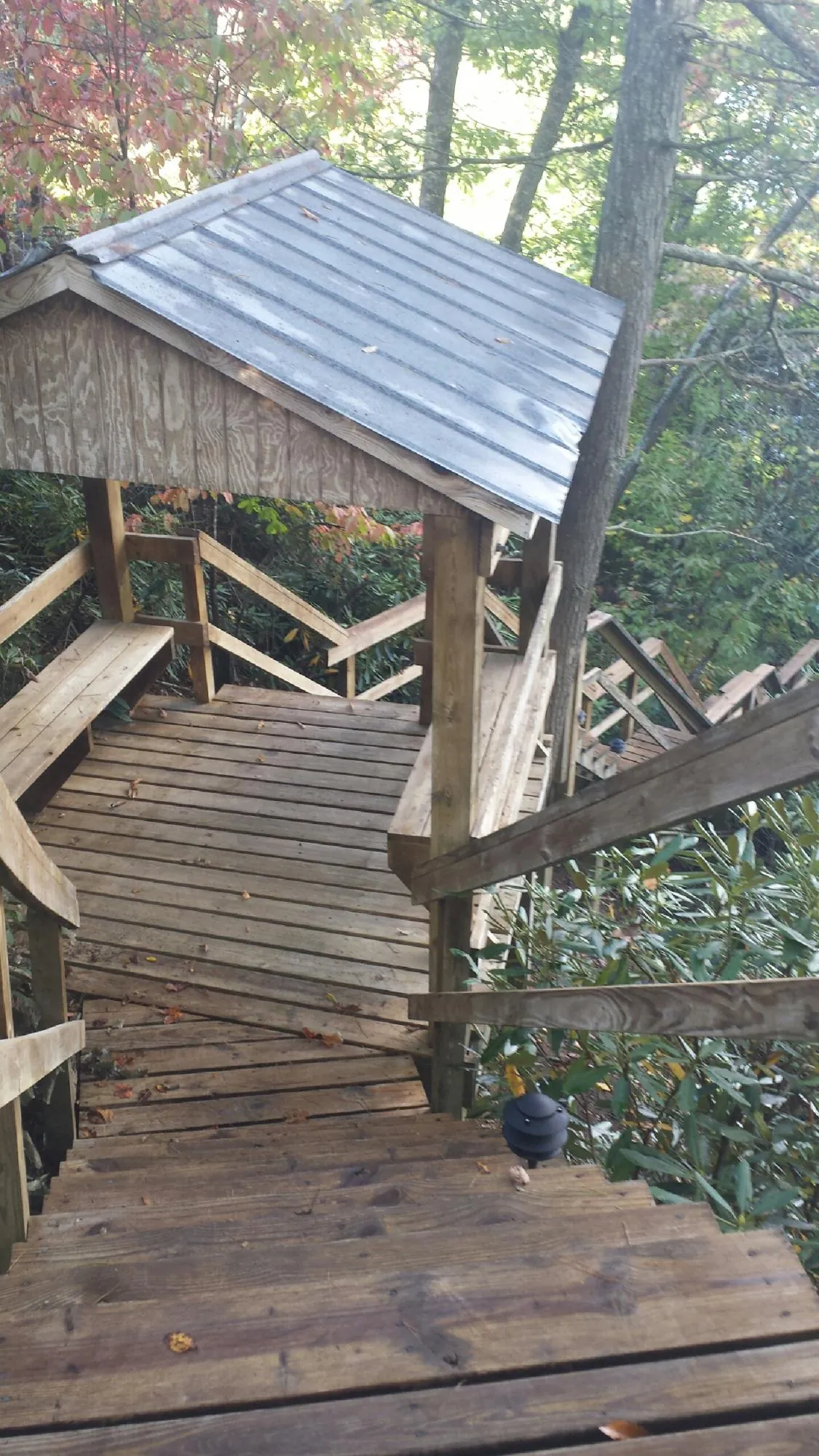 Metal roofed shelter over wooden steps on a wooded walkway — Skylight Repair & Installation work by our crew in Slovan