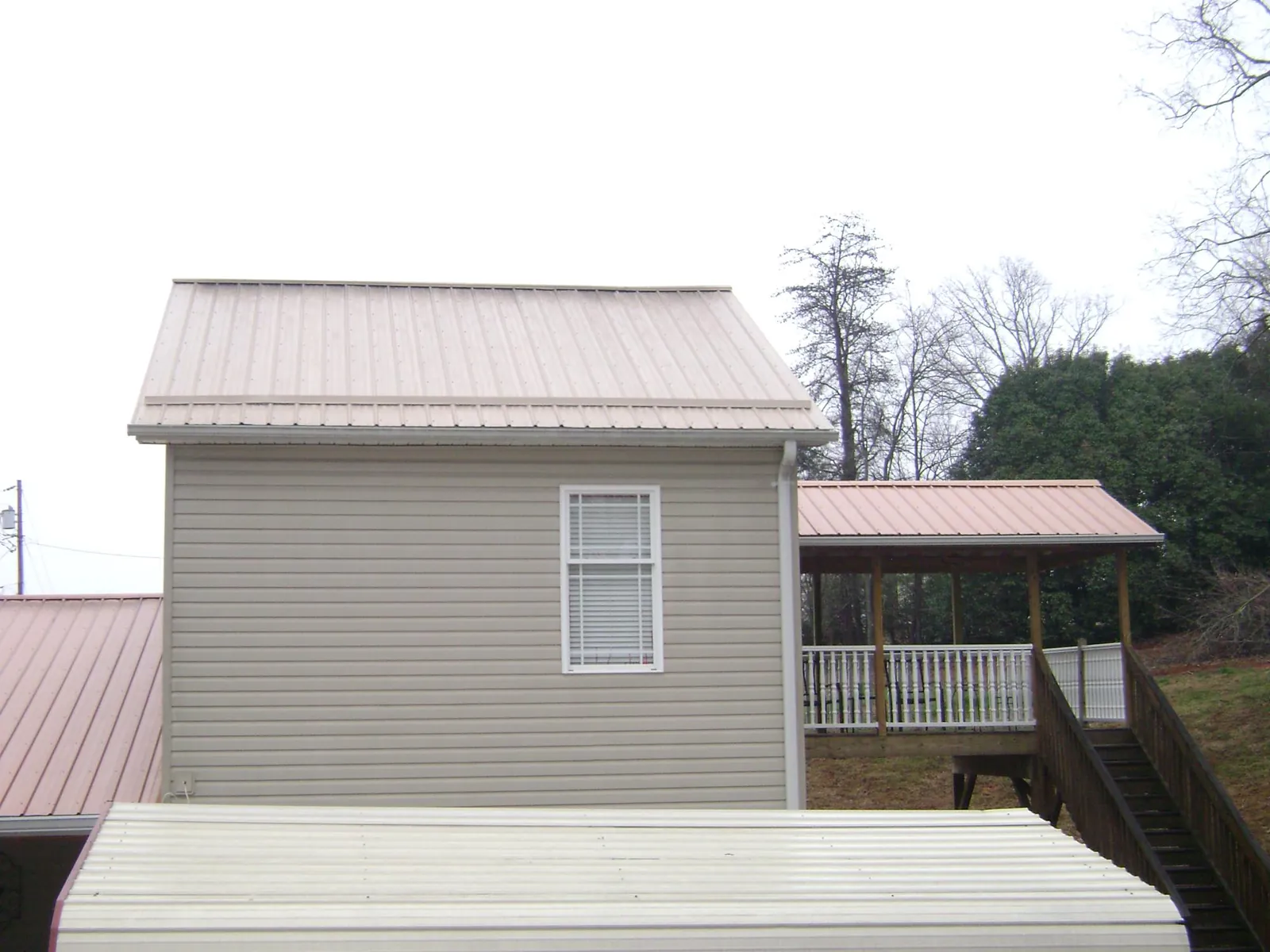 Tan metal roofs on a two story addition and attached porch, from a Roof Replacement job in Slovan