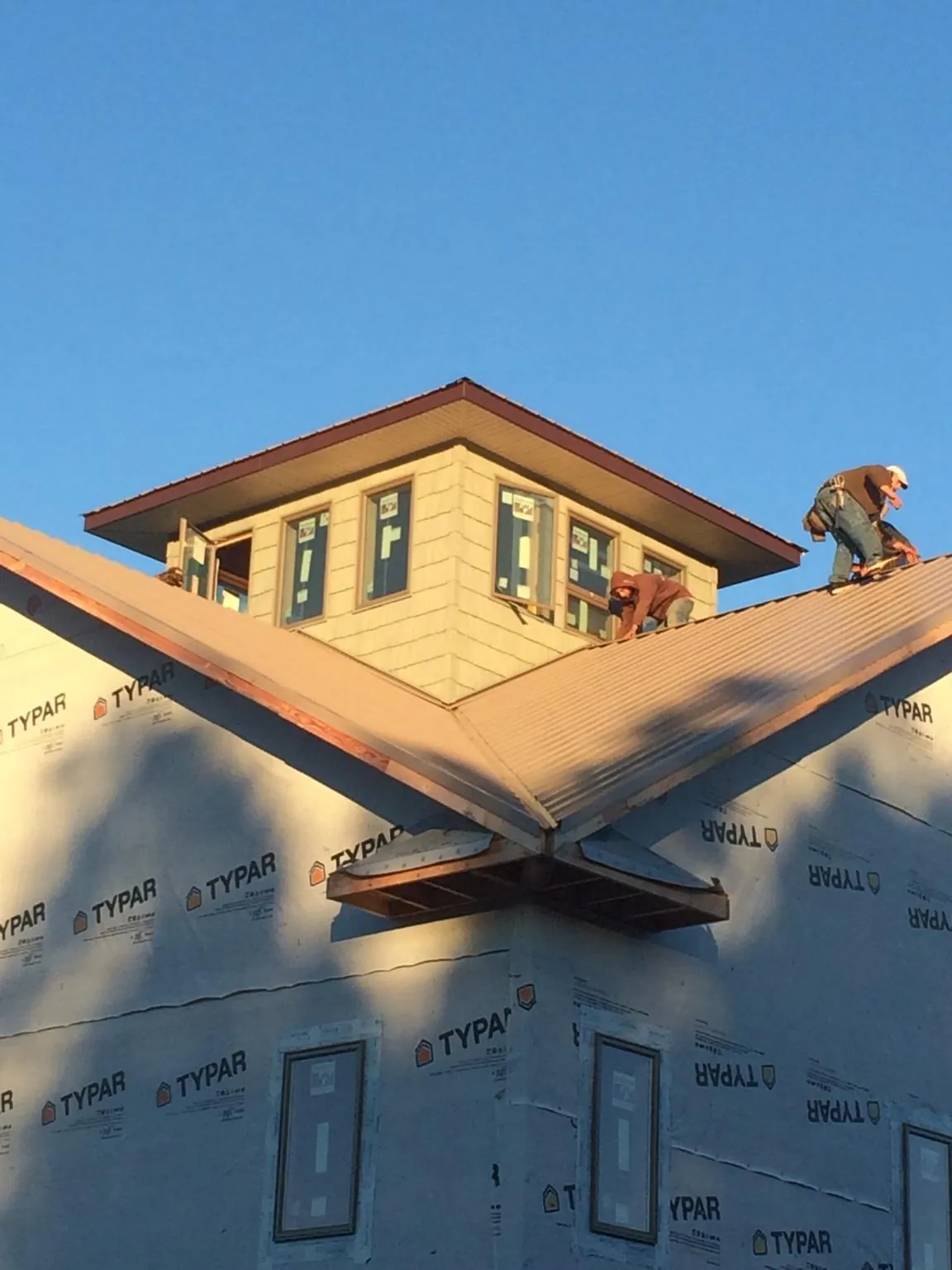 Roofers working around a rooftop cupola on a new metal roof at sunset — Roof Waterproofing in Slovan by Roofing Brothers